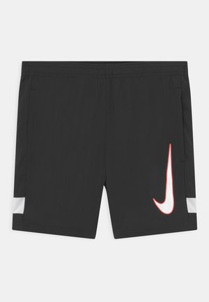 Shorts deportivos negros con cintura elástica, bolsillos laterales, un logo de Nike en blanco y rojo en la pierna derecha, y paneles de malla blanca cerca de las aberturas de las piernas.