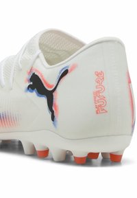 White soccer cleat with a textured finish, featuring black and orange accents, a prominent black logo, and colorful gradients on the side.