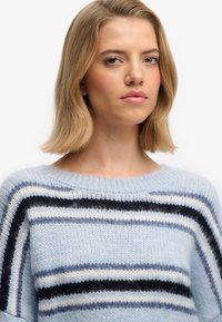 Hellblauer gestreifter Pullover aus weichem Strickstoff. Mit horizontalen Linien in Marineblau, Weiß und Hellblau. Rundhalsausschnitt, lockere Passform.