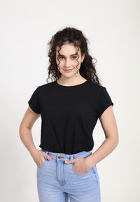 Sort kortærmet T-shirt med rund halsudskæring, lavet af glat stof, kombineret med lyseblå højtaljede jeans. Enkel, klassisk design.