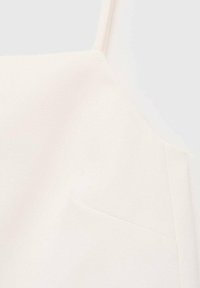 Top bianco senza maniche realizzato in tessuto liscio e opaco, con spalline regolabili e una discreta tasca laterale. Design semplice e minimalista.