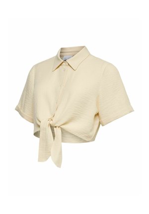 Chemise courte crème à boutons avec manches courtes et nœud devant, en tissu texturé.