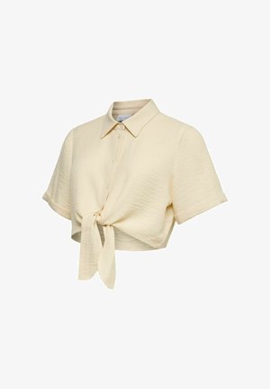 Chemise courte crème à boutons avec manches courtes et nœud devant, en tissu texturé.