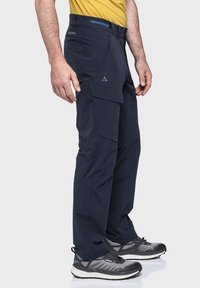 Dunkelblaues Outdoor-Hose mit mehreren Cargo-Taschen, glatter Textur, leichtem Glanz und figurbetontem Schnitt, getragen mit grauen Laufschuhen.