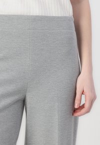 Gray elastic waistband pants with a smooth, textured finish. Features a close fit down the leg with a slight flare at the bottom.
