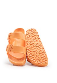 Sandalias moldeadas naranjas con dos correas ajustables, una suela de goma texturizada que presenta un patrón de olas y un acabado suave y brillante.