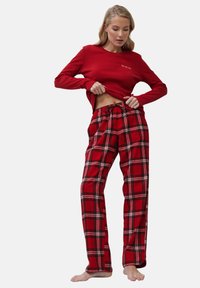 Camiseta roja de manga larga con bordado de "Ho Ho Ho"; pantalones de pijama de cuadros rojos y negros con cintura elástica y cordón. Tejido suave.