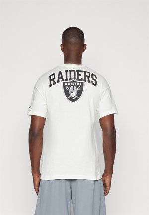Camiseta de algodón blanca con un gran texto y logo en negro de "RAIDERS" en la parte posterior. Manga corta y cuello redondo.