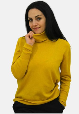 Maglione giallo a collo alto in maglia morbida con polsini e orlo a costine, design semi-slim. Il modello posa con una mano vicino al colletto.