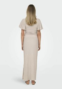 Vestido maxi texturizado en beige con mangas cortas acampanadas, cintura ajustada y una apertura lateral, hecho de una tela ligera.