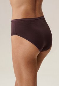 Ciemnobrązowa bielizna z wysokim stanem wykonana z miękkiego materiału, z gładkimi szwami i wygodnym krojem, przedstawiona z boku.