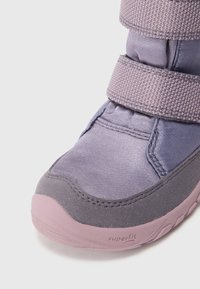 Lila Textilstiefel mit grauen Wildlederakzenten, ausgestattet mit zwei Klettverschlüssen und einer strukturierten pinkfarbenen Gummisohle. Die Marke "superfit" ist sichtbar.