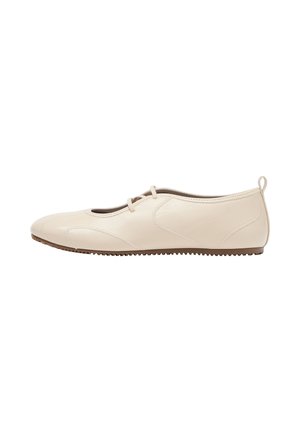 Chaussure plate en cuir beige avec bout arrondi, deux fines brides sur le dessus et une semelle marron texturée.