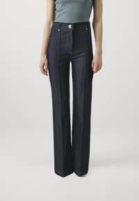 Jeans in denim scuro a vita alta con design a gamba dritta, dotati di cuciture a contrasto, chiusura con bottone e tasche frontali.