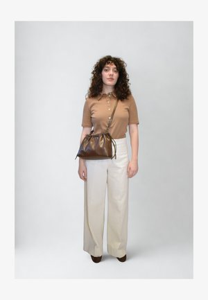 Barna rövid ujjú galléros póló; széles, krémszínű nadrág; sötétbarna, laza táska húzózsinórral; egyszínű világos háttér.