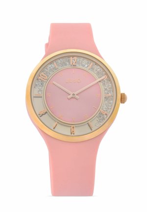 Montre-bracelet rose en silicone avec lunette en or, cristaux transparents autour du cadran, index dorés et deux aiguilles roses indiquant 10h10.