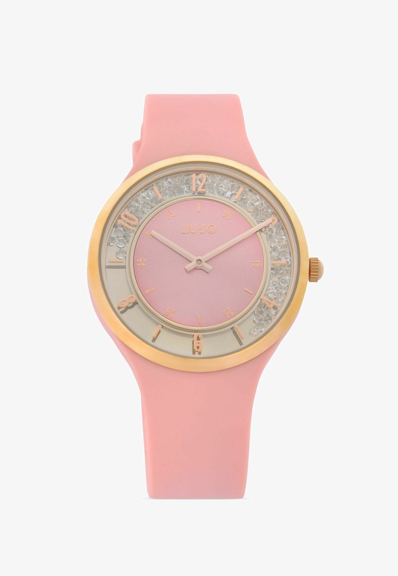 Montre-bracelet rose en silicone avec lunette en or, cristaux transparents autour du cadran, index dorés et deux aiguilles roses indiquant 10h10.