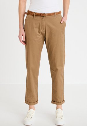 Jasnobrązowe chinosy o luźnym kroju, z bocznymi kieszeniami, plecionym jasnobrązowym paskiem i podwiniętymi nogawkami. Połączone z białymi trampkami na sznurowadła.
