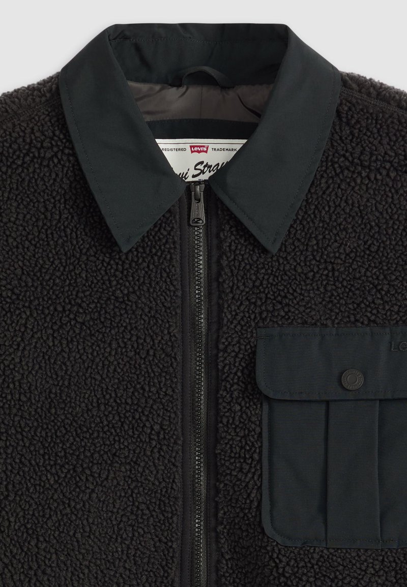 Zwarte fleecetrui met een contrasterende zwarte nylon kraag, voorrits en een patch pocket. Gekenmerkt door een zachte, pluizige afwerking.