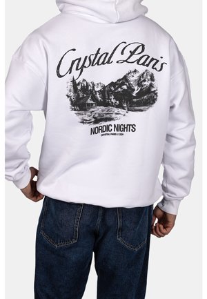 Biała bluza z kapturem z czarnym górskim krajobrazem, chatką i drzewami na plecach, zawierająca tekst "Crystal Paris" i "Nordic Nights."