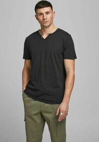 Sort V-hals T-shirt i blødt tekstureret stof, korte ærmer, parret med olivengrønne cargobukser med sidelommer med lynlås.