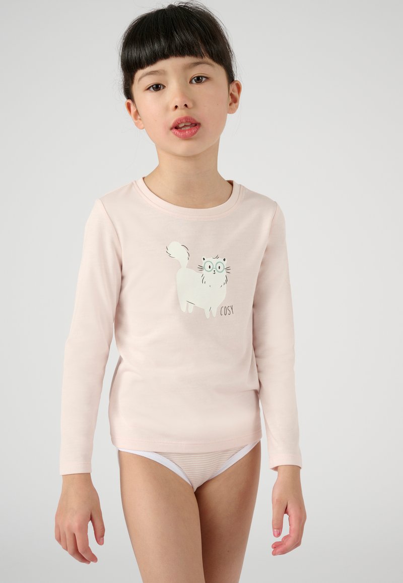 Chemise à manches longues rose clair avec un motif de chat cartoon blanc et le texte "COSY." Le tissu est lisse et la coupe est ajustée au niveau du torse.