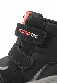 Scarpa nera per bambini con strap in velcro, con tomaia in tessuto testurizzato e dettagli lisci, con il marchio "reima TEC" in rosso.