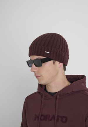 Béret tricoté bordeaux à côtes, associé à des lunettes de soleil rectangulaires noires. Modèle portant un hoodie bordeaux avec le texte "MORATO" dans une couleur assortie.