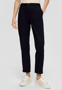 Pantalon en coton bleu marine, coupe droite, avec une ceinture dotée d'une boucle en argent, poches latérales et ourlets retroussés, accompagnés de chaussures beiges.