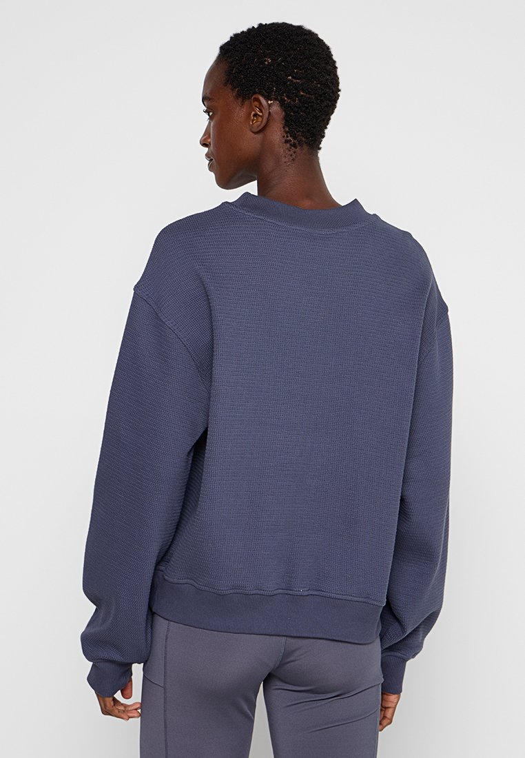 Oversized marineblauwe sweatshirt van textuurstof, met geribbelde ronde hals en aansluitende mouwen. Eenvoudig ontwerp, geschikt voor casual wear.