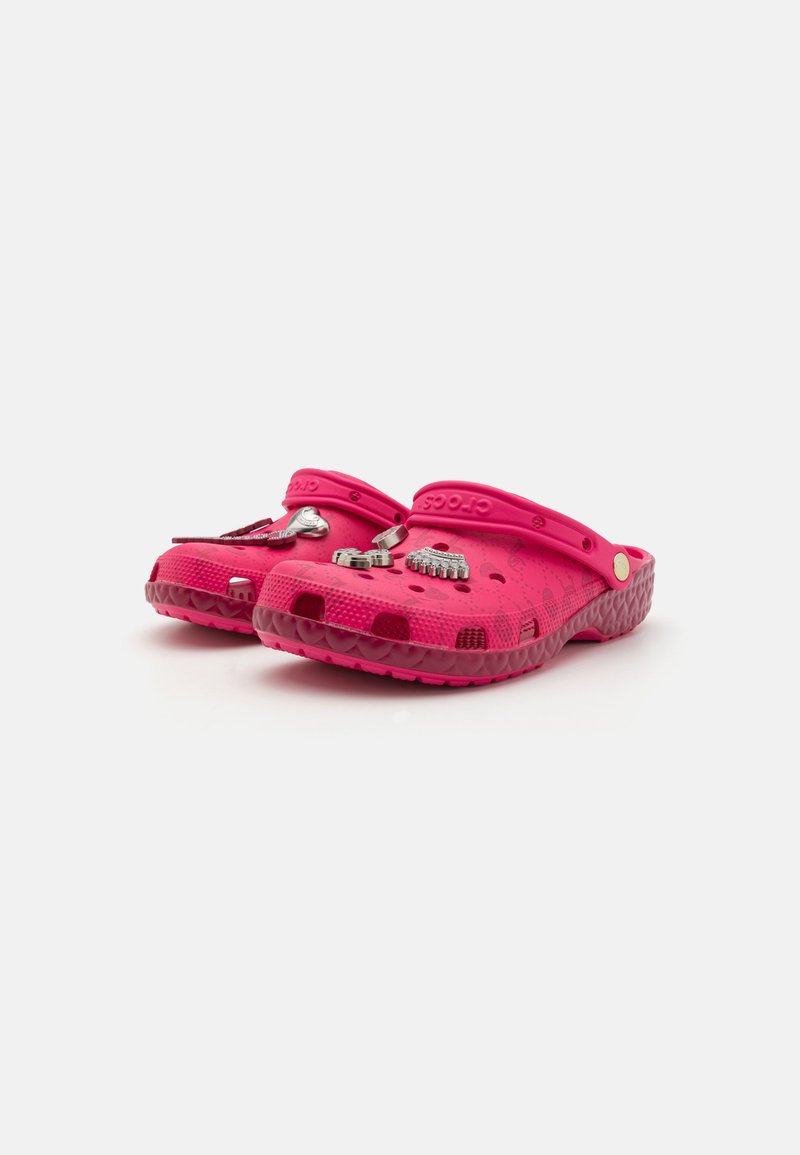 Las zuecos de Crocs en color rosa cuentan con una amplia caja para los dedos, orificios de ventilación y una correa ajustable. Tienen una textura suave con material similar al caucho y una suela con patrón.