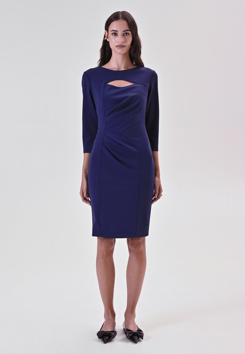 Marineblaues knielanges Kleid mit dreiviertelärmel, das einen Front-Ausschnitt und Drapierungsdetails aufweist. Glattes Material mit einem figurbetonten Schnitt.