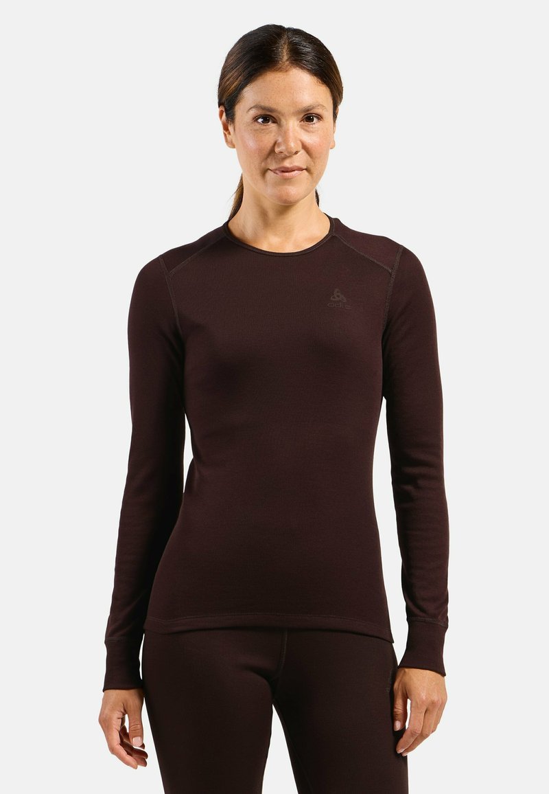 Long-sleeve, fitted thermal top in dark brown, ribbed texture, features a crew neck and subtle branding on the chest. Soft, stretch fabric.