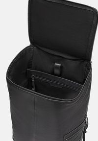 Sac à dos en cuir noir avec fermeture éclair, doté d'un intérieur spacieux et d'une petite poche zippée. Le tissu intérieur est noir, avec une texture lisse.