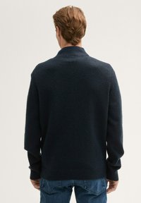 Pull en navy foncé avec un tricot texturé, présentant un col châle et des poignets côtelés. La vue de dos montre une coupe décontractée et des manches longues.