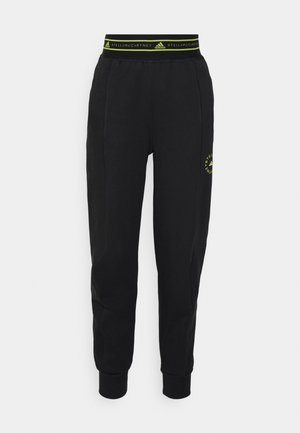 Musta urheilulliset jogger-housut, joissa kuminauhavyötärö ja Adidas- sekä Stella McCartney -logot kelta-vihreänä. Resorit nilkoissa.