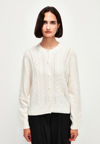 Bílý pletený cardigan s kabelovým vzorem, kulatým výstřihem a perlami na knoflících, s dlouhými rukávy a měkkou, strukturovanou tkaninou.