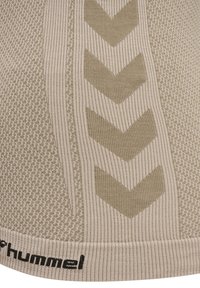 Beżowa teksturowana dzianina z żebrowanymi wzorami w jodełkę i czarnym napisem marki „hummel” na dolnej krawędzi.