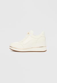 Zapatillas blancas con un diseño texturizado, puntera redondeada, cierre de cordones y un tacón cuña acentuado por una raya dorada. Suela de goma.