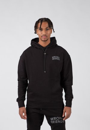 Black hooded sweatshirt made of cotton, featuring a drawstring, front pocket, and "WRONG FRIENDS" logo in gray on the chest and pants.