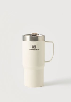 Gobelet de voyage Stanley blanc en acier inoxydable avec poignée et couvercle argenté, debout sur fond uni.