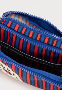 Μικρή θήκη με κάθετες ρίγες σε μπλε, κόκκινο και μαύρο, ανοιχτό μπλε φερμουάρ και μαύρη υφασμάτινη επένδυση με το κείμενο "marimekko" στο εσωτερικό.