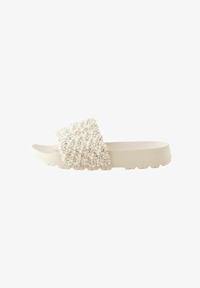 Sandale beige à enfiler avec des ornements texturés, ressemblant à des perles, sur une large bride supérieure et une semelle rainurée pour une bonne adhérence.