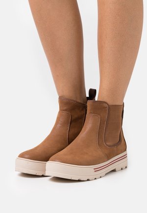Bottes chevilles marron en cuir lisse avec inserts latéraux élastiques, panneaux texturés et une semelle en caoutchouc blanche avec des bandes rouges.