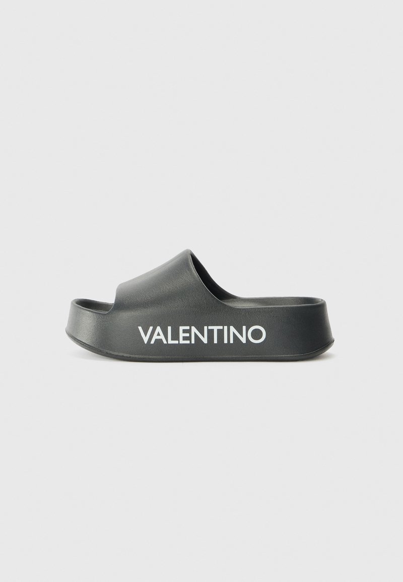 Papuci negri cu talpă din material moale, având un design curbat. Prezintă o curea largă și un logo „VALENTINO” embosat în alb pe margine.
