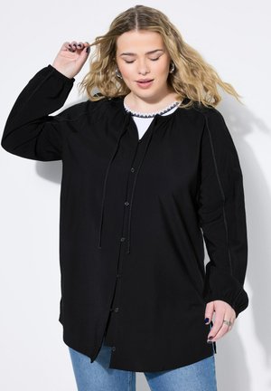 Camisa negra de botones con escote fruncido, puños elásticos y detalle de cordón. Presenta costuras en contraste y una tela ligera.