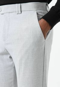 Lichtgrijze broek met een gestructureerde stof, een getailleerd ontwerp, zijzakken en een nette tailleband met een knoopsluiting.