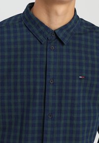 Knapp-up skjorta i mörkgrön och marinblå rutigt mönster, med en strukturerad krage, framknappar och en liten logopatch.