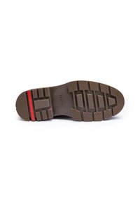 Suela de zapato de goma marrón con un acabado texturizado, que presenta un patrón de profundas ranuras y acentos en rojo y negro. Marca LLOYD visible.