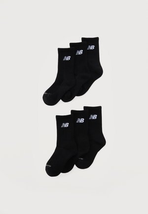 Sei paia di calzini da equipaggio neri con polsini a coste, ciascuno con un logo bianco "NB" vicino alla parte superiore, disposti in due gruppi di tre paia su sfondo bianco.